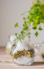 Fragrant seasoning, green salt with a mixture of herbs in a glass jar on a wooden background.