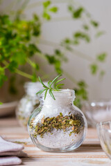 Fragrant seasoning, green salt with a mixture of herbs in a glass jar on a wooden background.