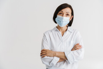 European mature woman in face mask posing with arms crossed