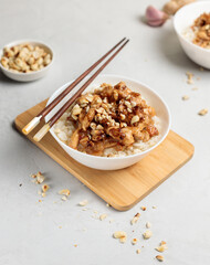 Bowl with chinese food. Kung pao, rice with chicken fillet in sauce. Close-up on a light background, vertical