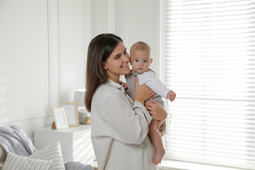 Young woman with her little baby near window at home