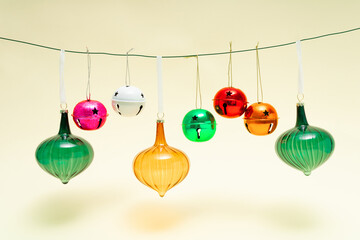 Christmas vintage ornaments in vivid colors hanging on the rope against pastel beige background. Winter holidays and New Year celebration concept. Retro 80s or 90s aesthetic.