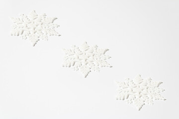Christmas creative pattern made of white snowflakes with glitter on white table. Winter holidays and New Year monochrome aesthetic background.