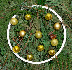 Christmas round frame with natural evergreen branches and sparkle golden baubles. Creative winter holidays and New Year arrangement. Natural background.