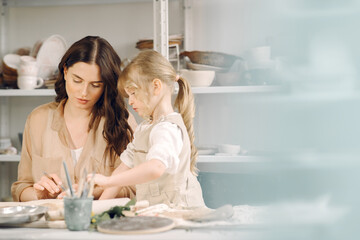 Portrait of mother and little girl shaping clay together