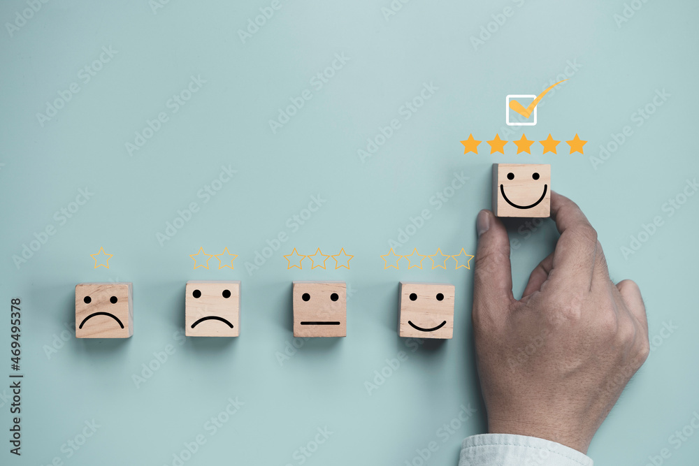 Poster Hand holding and move up wooden cube block which print screen smiley face with five stars for client customer satisfaction after use product and service concept.