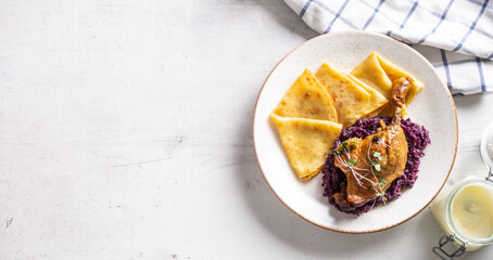 Portion of duck leg with red cabbage and potato pancakes, a traditional autumn dish in Eastern...
