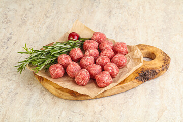 Obraz na płótnie Canvas Raw uncooked beef meatballs served rosemary