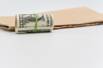 isolated US dollar banknotes roll on a white and brown paper background with copy space