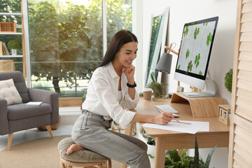 Young woman working at table in light room. Home office