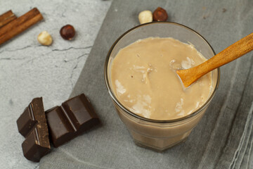 Caramel chocolate pudding on a gray table with chocolate and nuts.