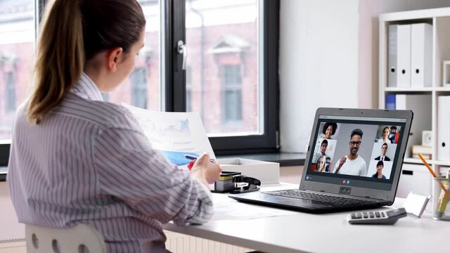 remote job, technology and people concept - young businesswoman with laptop computer and papers working at home office and having video conference
