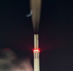 Rauchender Industrieschornstein bei Nacht