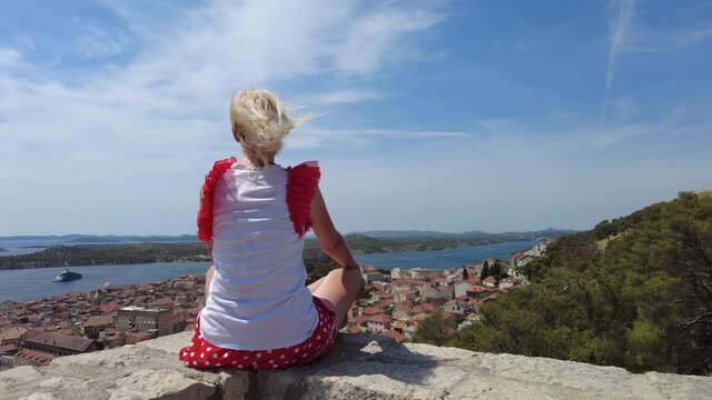 Woman on walls of the Barone Fortress looking at the cityscape of Sibenik. Skyline with St. Michael castle and St. John's Fort. Sibenik historic city of Croatia in Dalmatia. It was of Venice Republic.