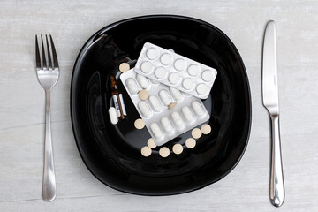 fork and knife on plate with many pills 