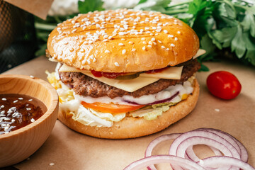 Classic double burger with meat cutlet, lettuce, tomato, pickled cucumber, cheese, onion and sauce on craft paper