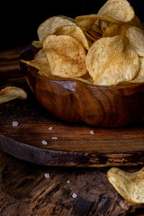 Potato chips on a wooden bowl over wood background