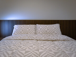 detail of pillows and headboard in slatted dark wood