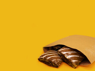 Cookies in a kraft bag on a yellow background with space for presentation.