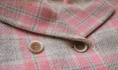 Buttons placed on a fabric plaid wool jacket. Close up image.