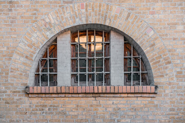 Wooden arch window of medieval fortress with iron protection grate. Old. History. Architecture. Brick wall