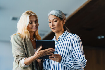 Adult multiracial women working with tablet computer in office
