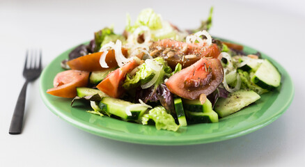 vegetable salad of greens, tomatoes and cucumbers on a green plate