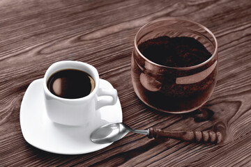 coffee in a cup on a stone stand ground coffee in a glass jar vintage coffee spoon, wooden natural background, selektive focus