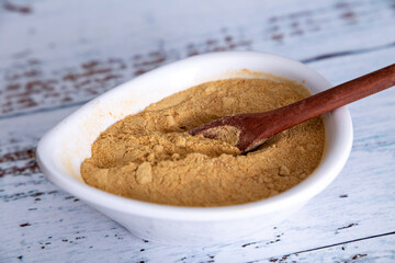 pot with Peruvian maca powder and rustic wooden spoon. On a white wooden background