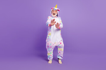 Photo of excited handsome man pensioner unicorn sleepwear dancing smiling isolated violet color background