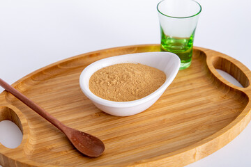 pot of Peruvian Maca powder under a bamboo tray, selective focus, on white background.