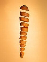 Sliced floating carrot on orange background