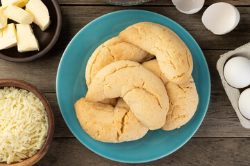 Chipas, typical south american cheese bun over wooden table with ingredients