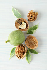 Walnuts with nut peel on white wooden background