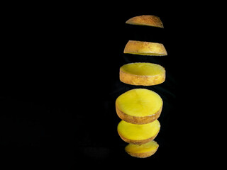 Sliced potato floating on black background