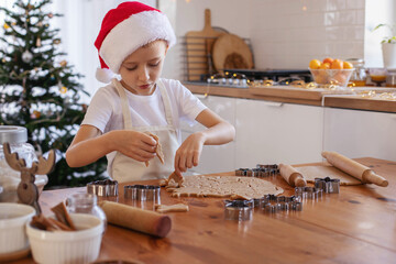Children with their mother cut out Christmas gingerbread cookies on the table from rolled dough.