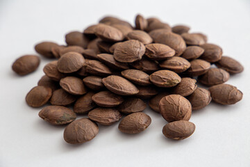 Sacha Inchi roasted seed nuts, selective focus on front seeds, on white background