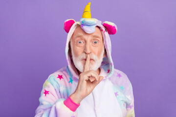 Portrait of attractive mysterious grey-haired man wearing kigurumi showing shh sign isolated over violet purple color background