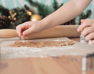 Close-up of children's hands cutting ginger cookies out of dough. Little girl making Christmas cookies. Christmas holidays, moments