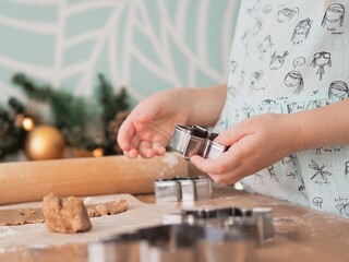 Close-up of children's hands cutting ginger cookies out of dough. Little girl making Christmas cookies. Christmas holidays, moments