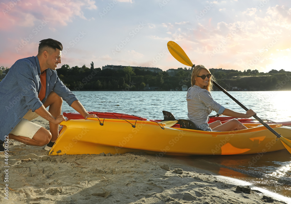 Canvas Prints Man helping woman on kayak at riverside. Summer activity