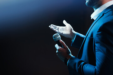 Motivational speaker with microphone performing on stage, closeup. Space for text - obrazy, fototapety, plakaty