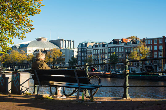 men sitting on the bench near river Amstel - Powered by Adobe