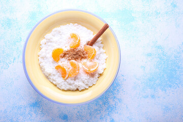 Rice pudding with cinnamon and tangerines on blue background