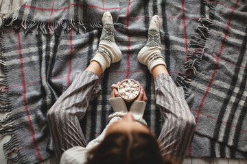 Hands of a woman holding a mug of hot chocolate or coffee