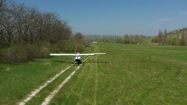 A light plane take off. The Small civil private aircraft takes of from the green field. Aerial view.