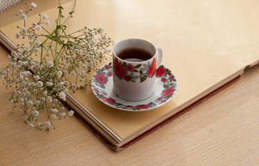 cup of coffee on top of a clear wooden table with white flowers round