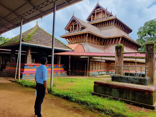 A man standing in front of the ancient Hindu temple rich in architecture design and wood carvings located in Adoor Kerala