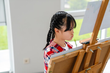 Asian girl drawing during class in art school indoors