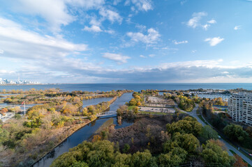Fototapeta na wymiar Drone views of Humber bay park overlooking the lake and fall tree colours by Parklawn and lakeshore with blue sky and clouds 